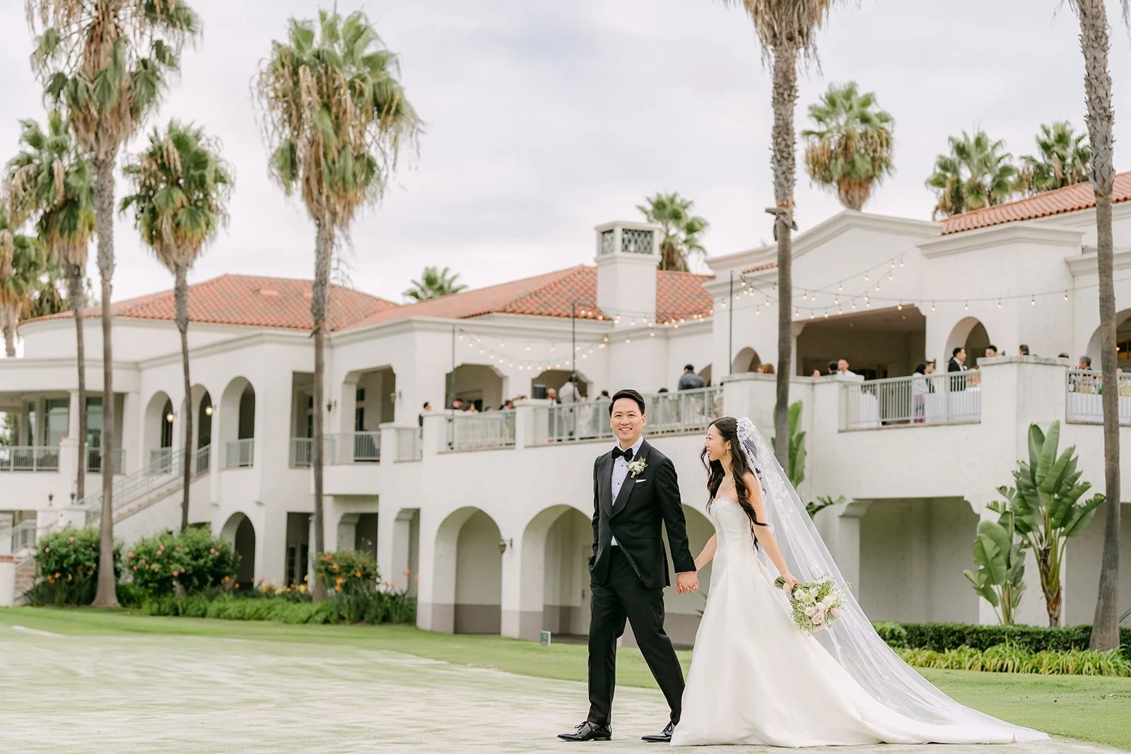 Kristine and William walking hand in hand past the clubhouse terraces
