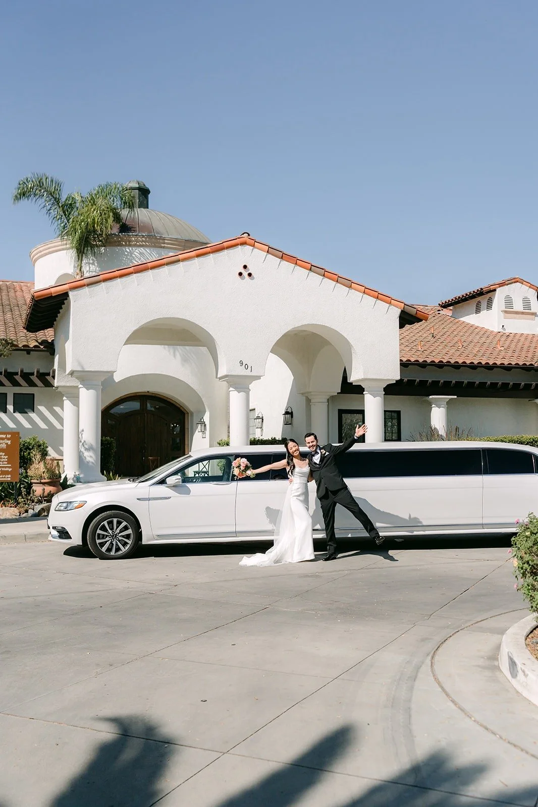 Stephanie and Kevin by the limo under the red tile roofline, photographed by One and Only Production