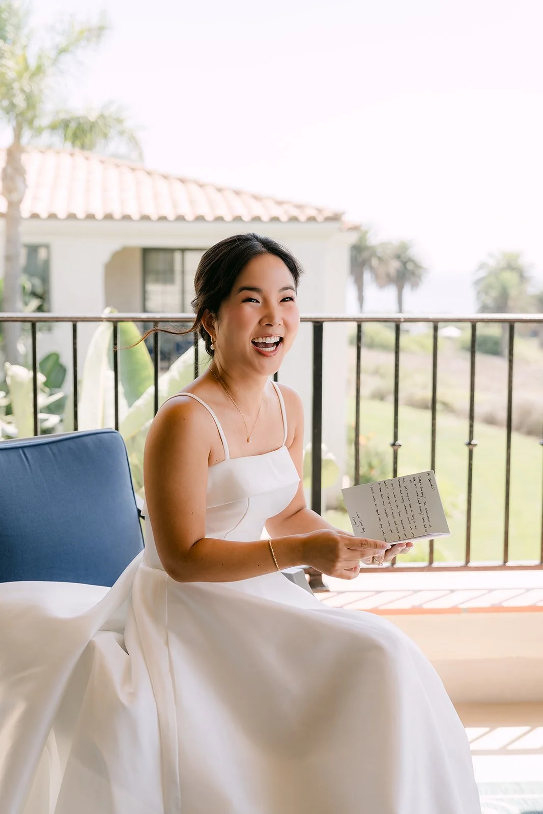 Saya laughing while reading a card on the balcony