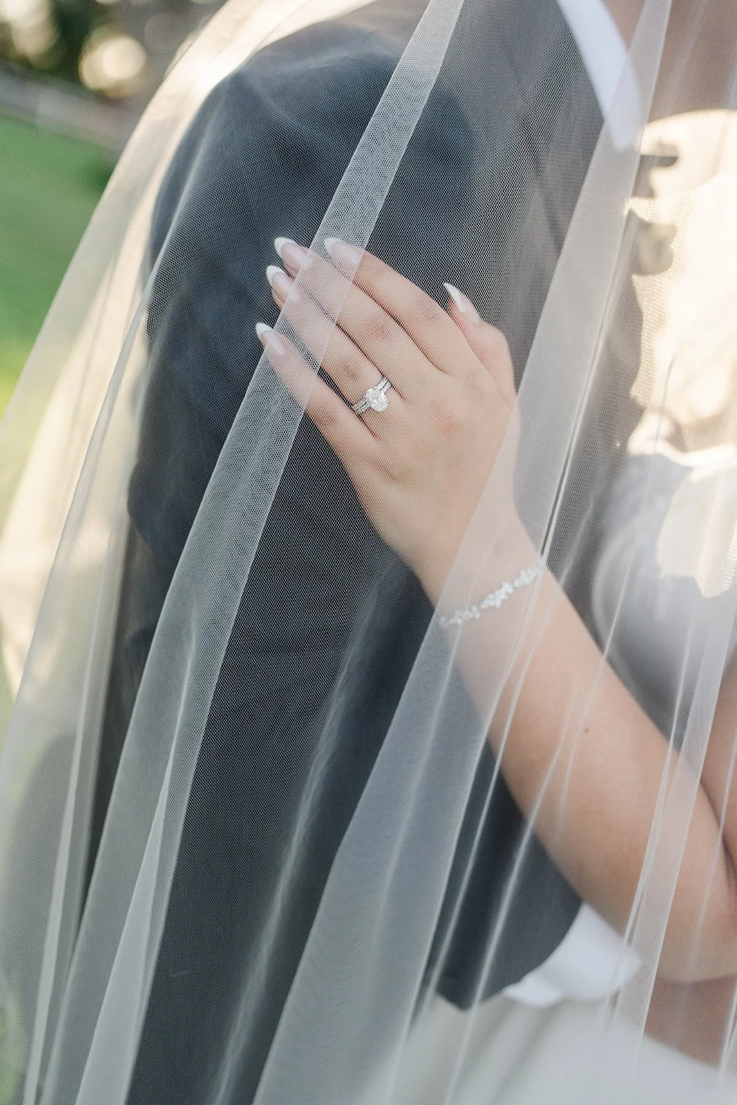 Bride's hand with ring on the groom's face under her veil