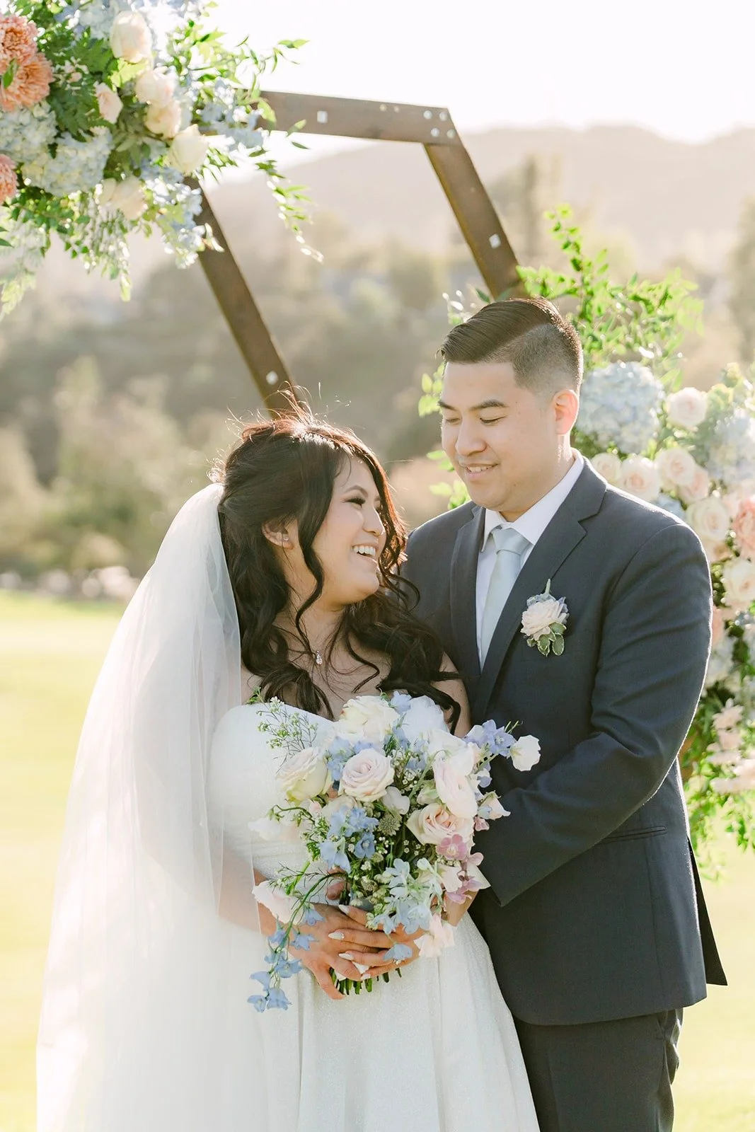 Florence and Jordan smiling under the floral arch