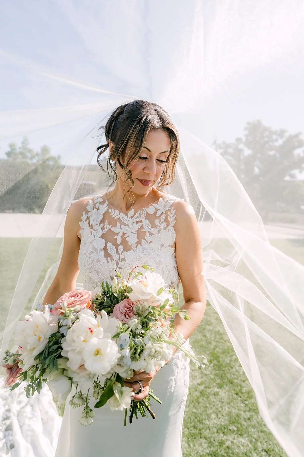 Francesca holds her blush and white bouquet as her veil catches the breeze