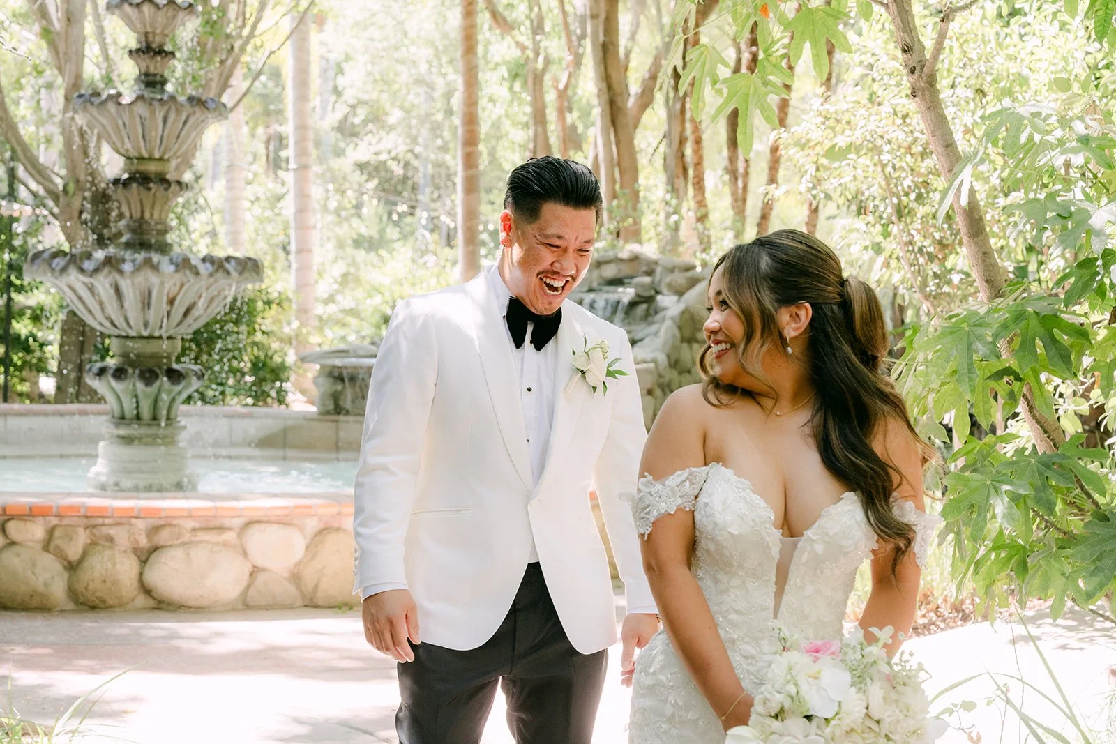 Caryl and Nicole smiling together after their first look by the fountain at Eden Gardens.