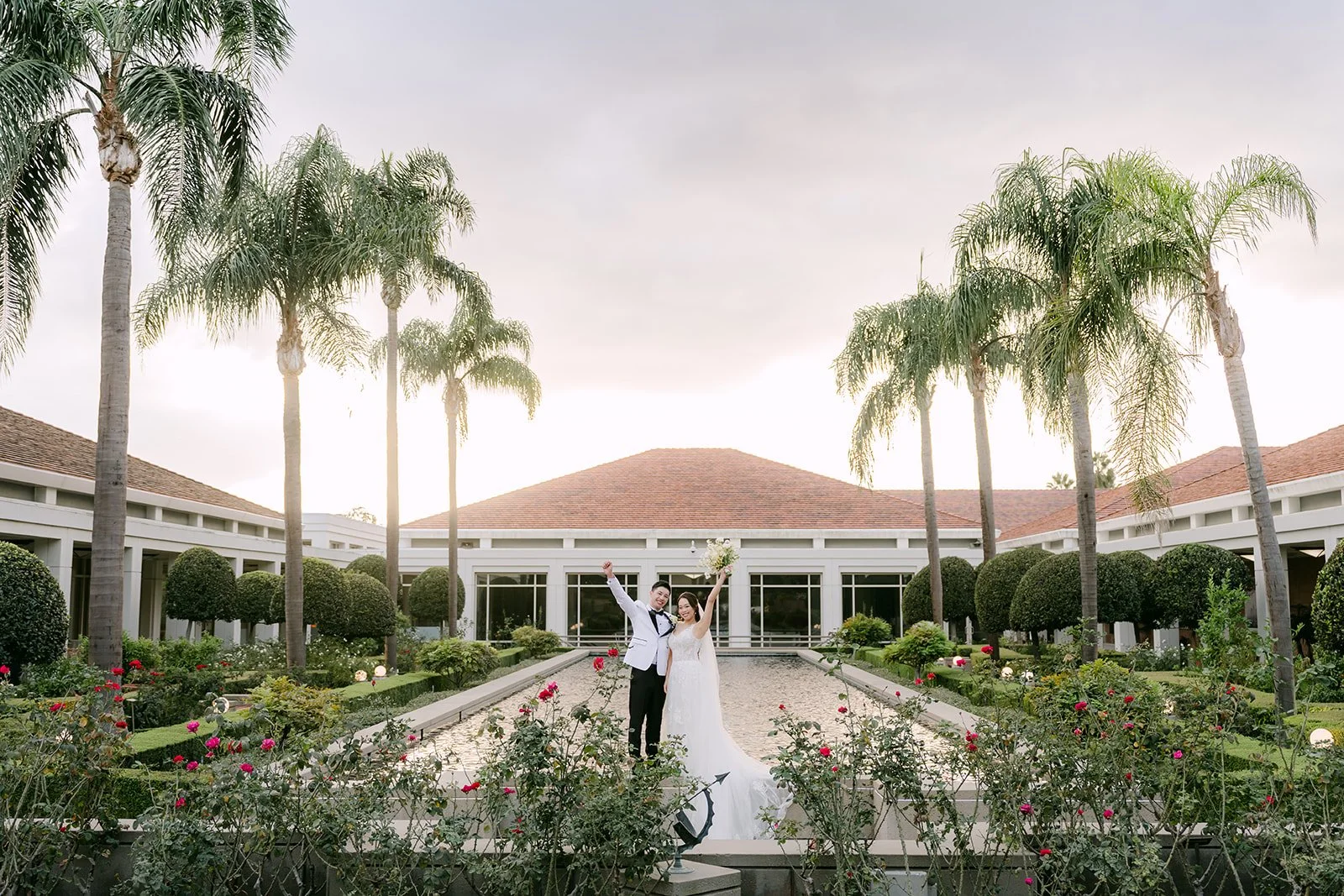 Jenny raising her bouquet beside Ryan at the reflecting pool.
