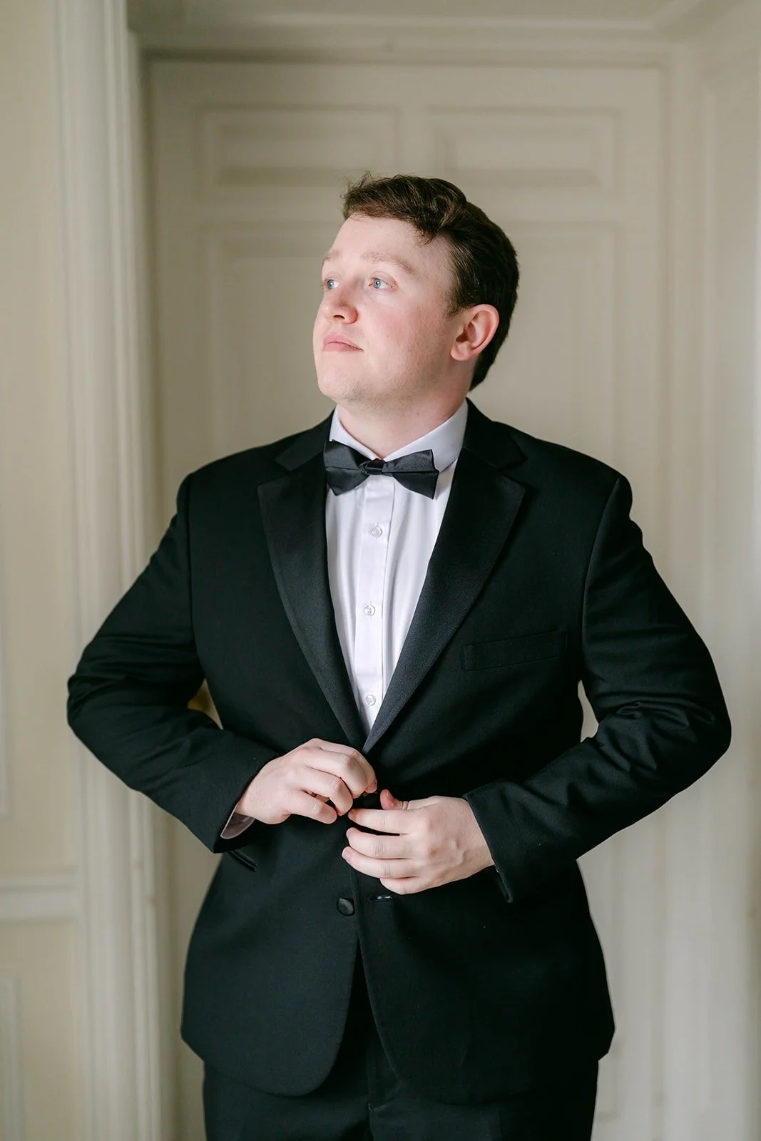 Matthew buttoning his black tuxedo jacket