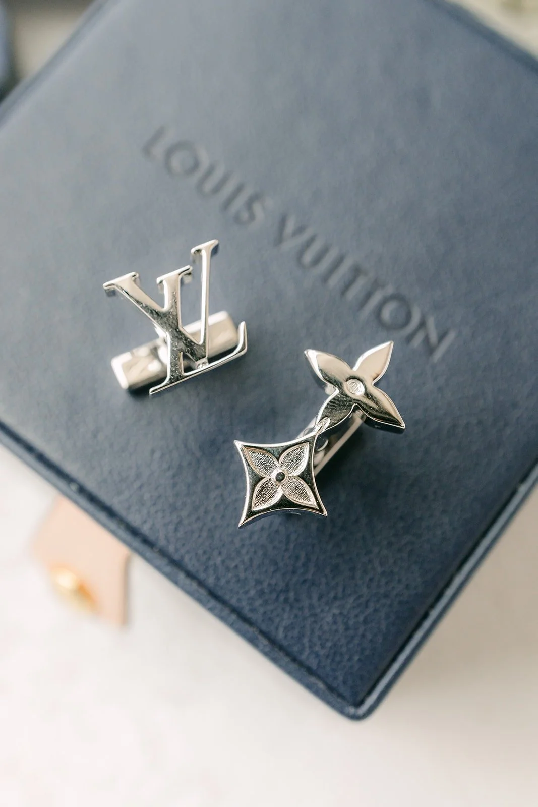 Silver cufflinks resting on a navy gift box