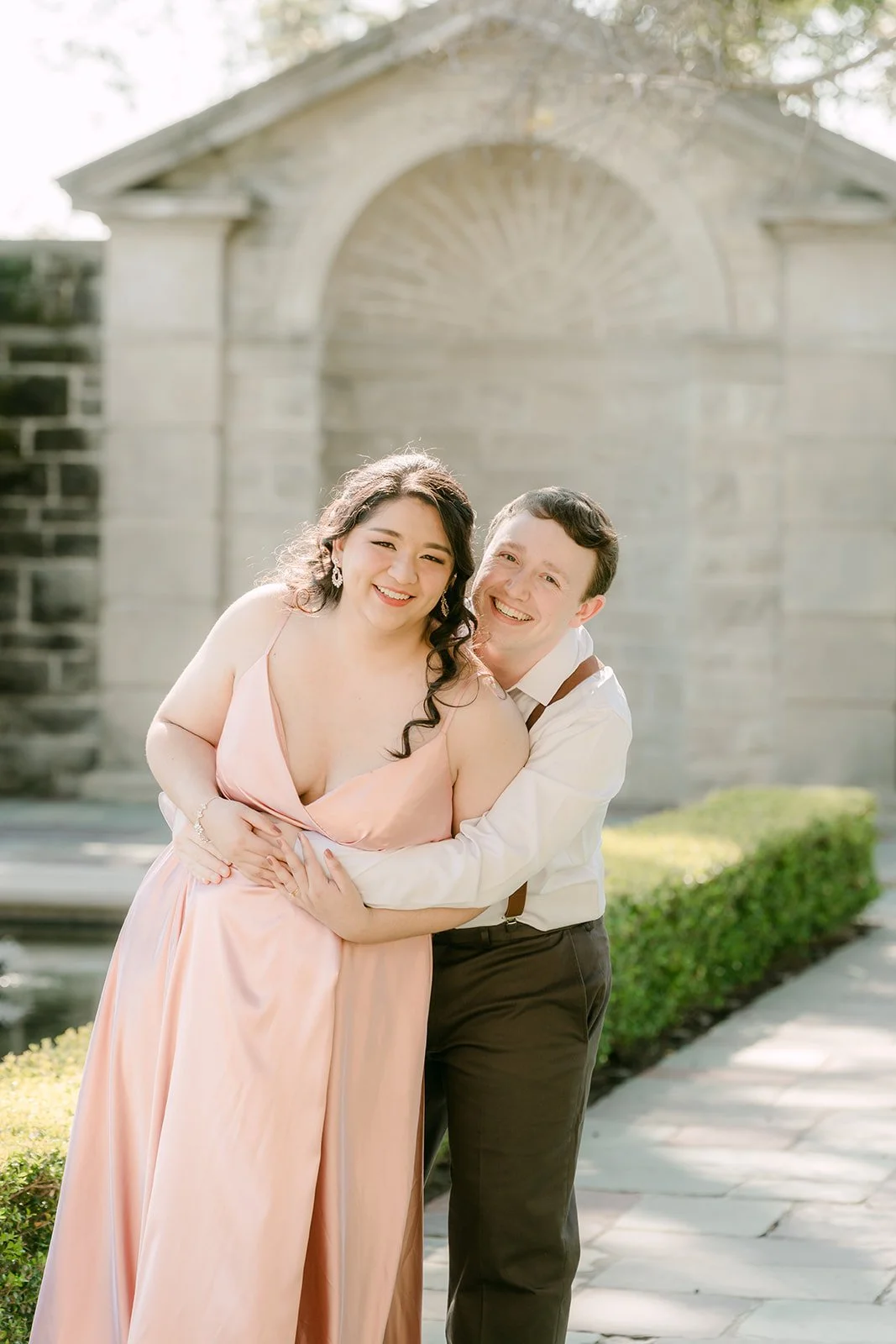 Saira and Matthew laughing in front of the stone pavilion at the reflecting pool.