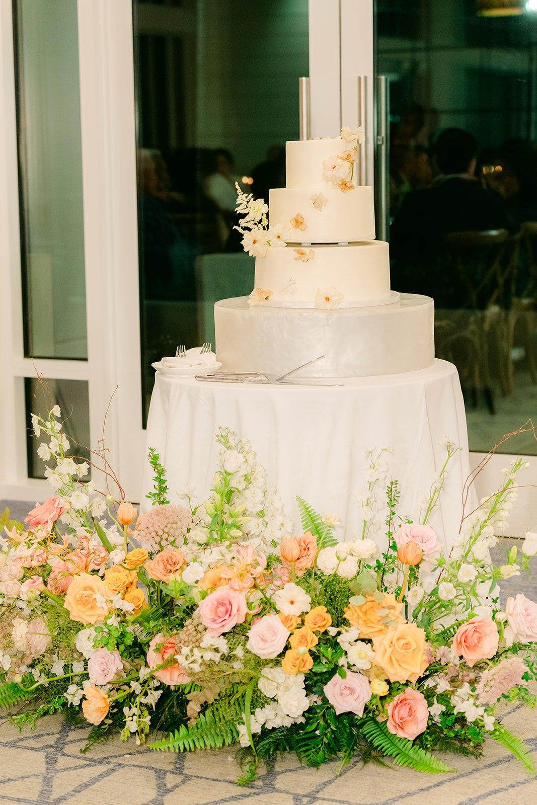 The four tier white wedding cake on a bed of peach florals