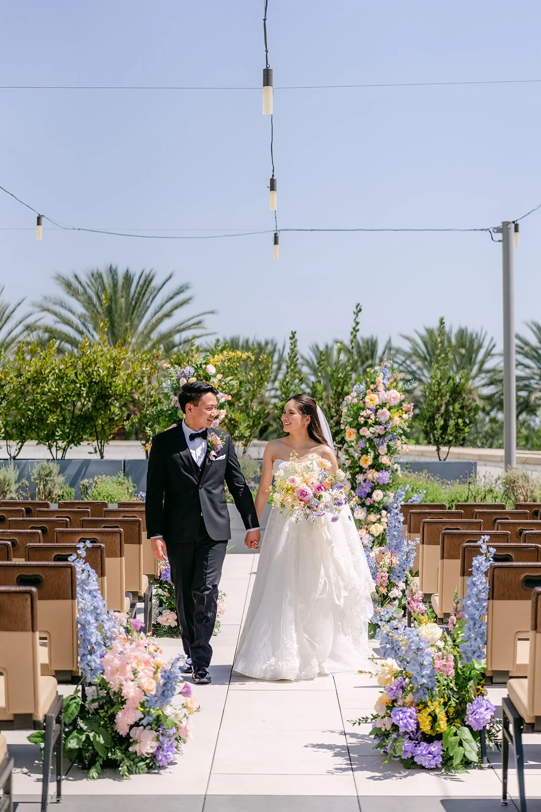 Couple walking down the Serenity Garden aisle under string lights