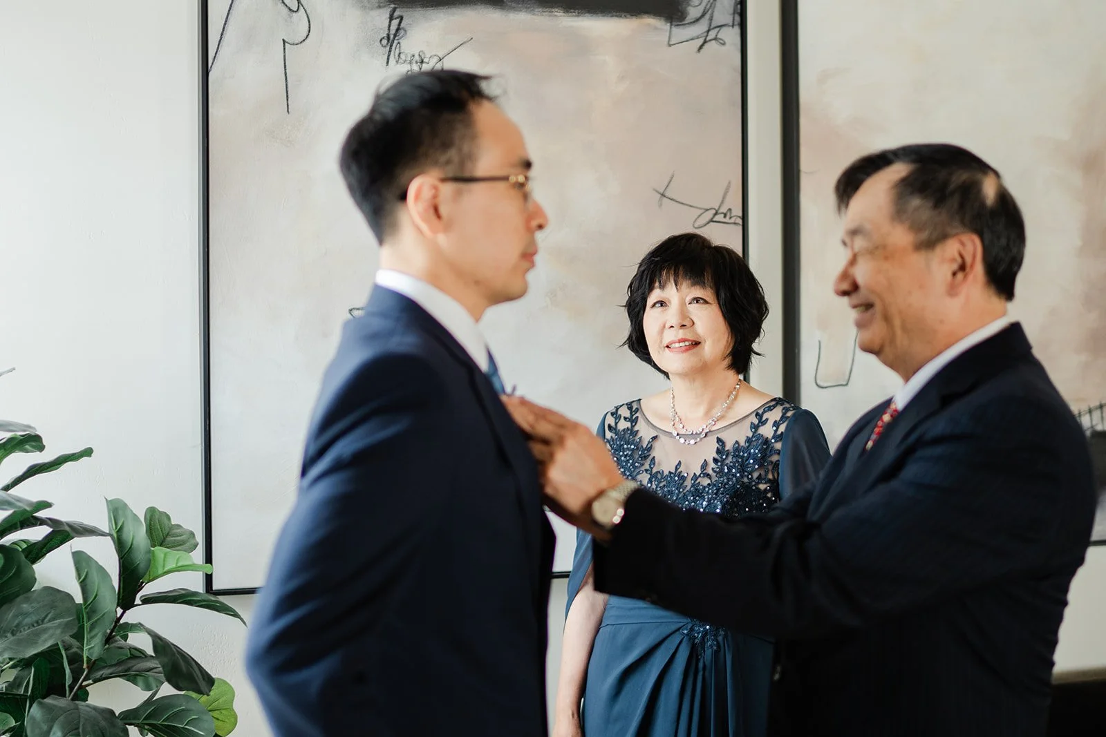 Lawrence's parents helping with his tie in the groom's suite
