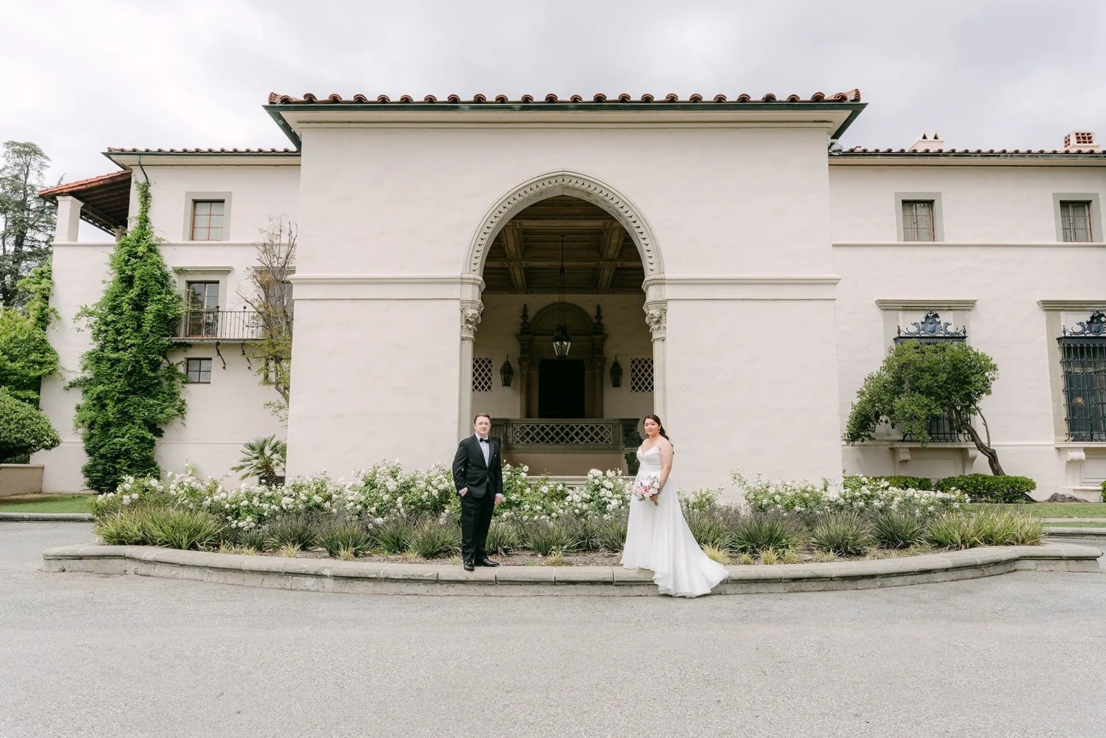 Saira and Matthew in front of the arched entrance of The Athenaeum at Caltech in Pasadena
