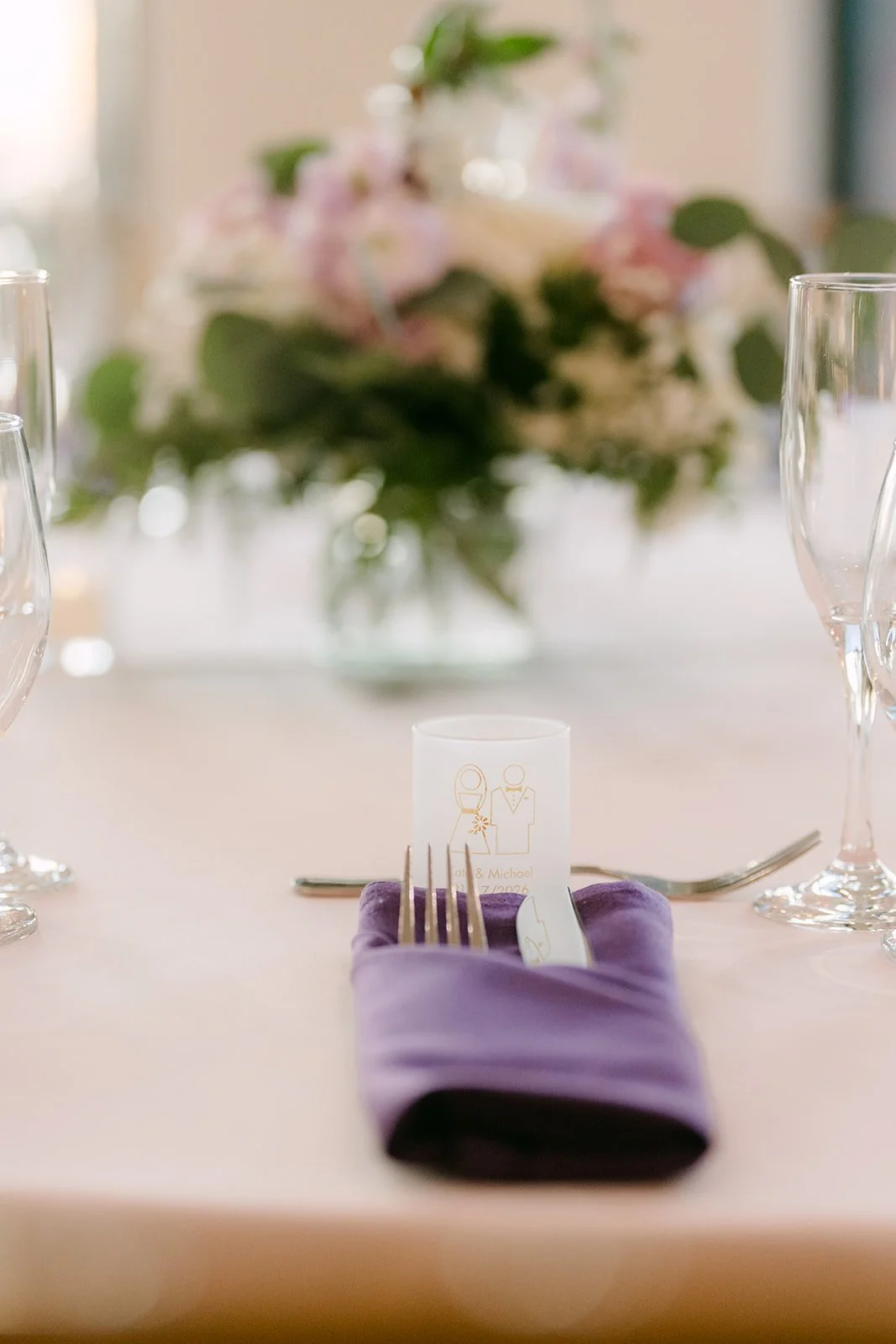 A place setting with a lilac napkin and centerpiece.