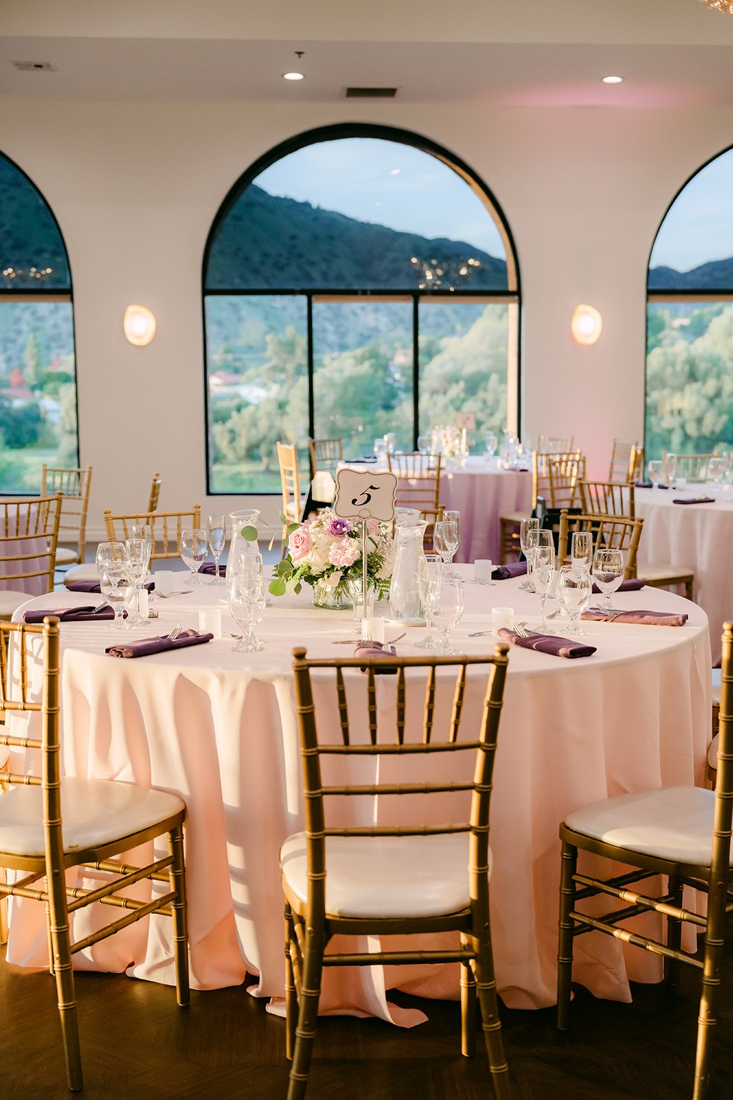 Guest tables beneath the arched windows of the ballroom.