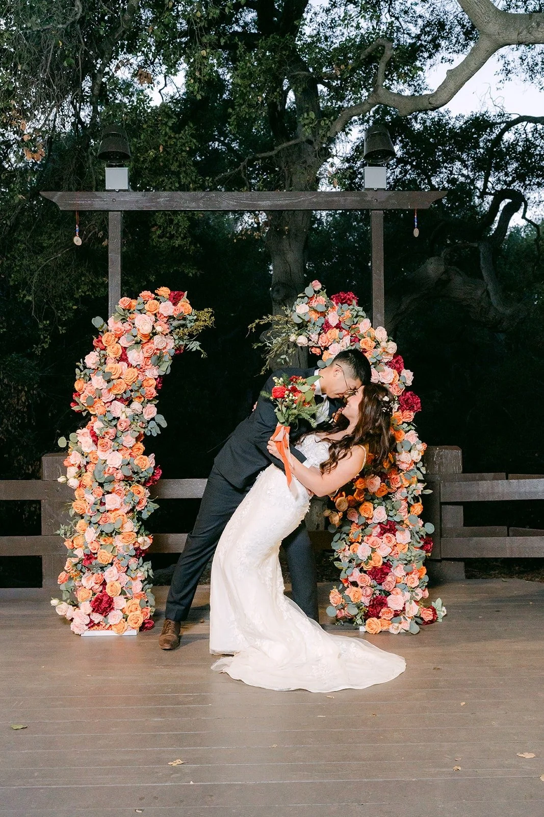 Robert dips Shayna in front of the floral ceremony arch after dark