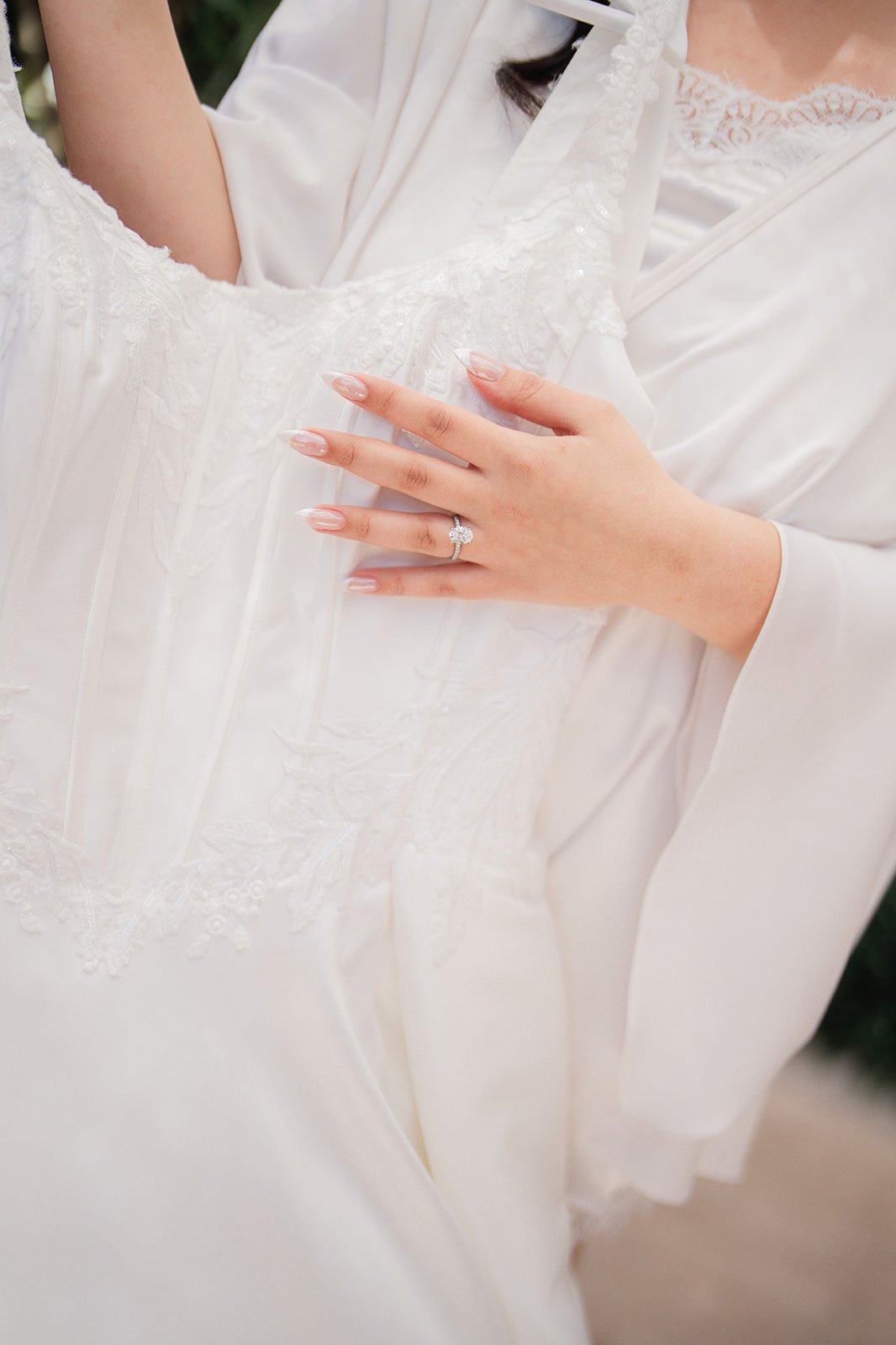 Bride's hand with engagement ring resting on her gown
