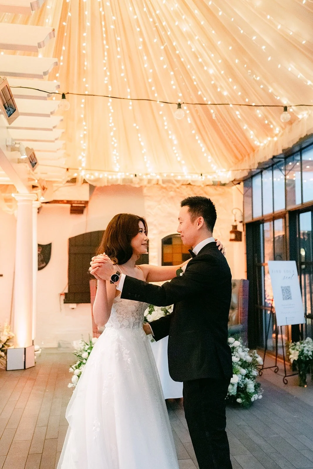 Jason and Valerie dancing close under the string lights