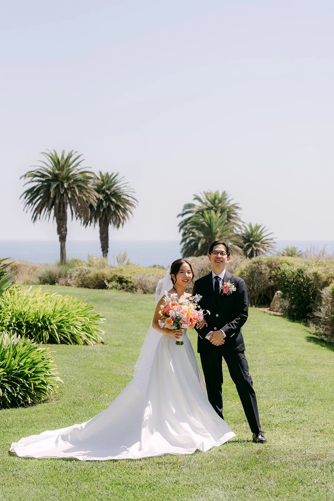 The newlyweds-to-be on the bluff lawn framed by palm trees