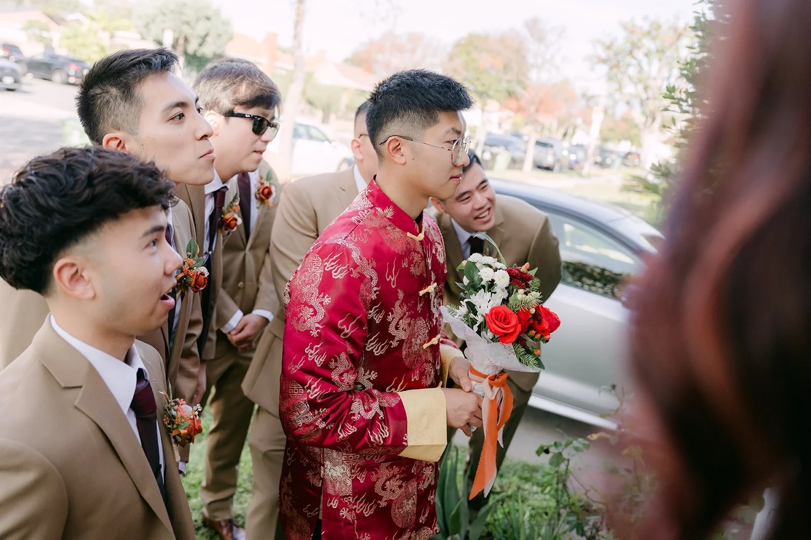 Robert in a red Chinese jacket with his groomsmen at the door