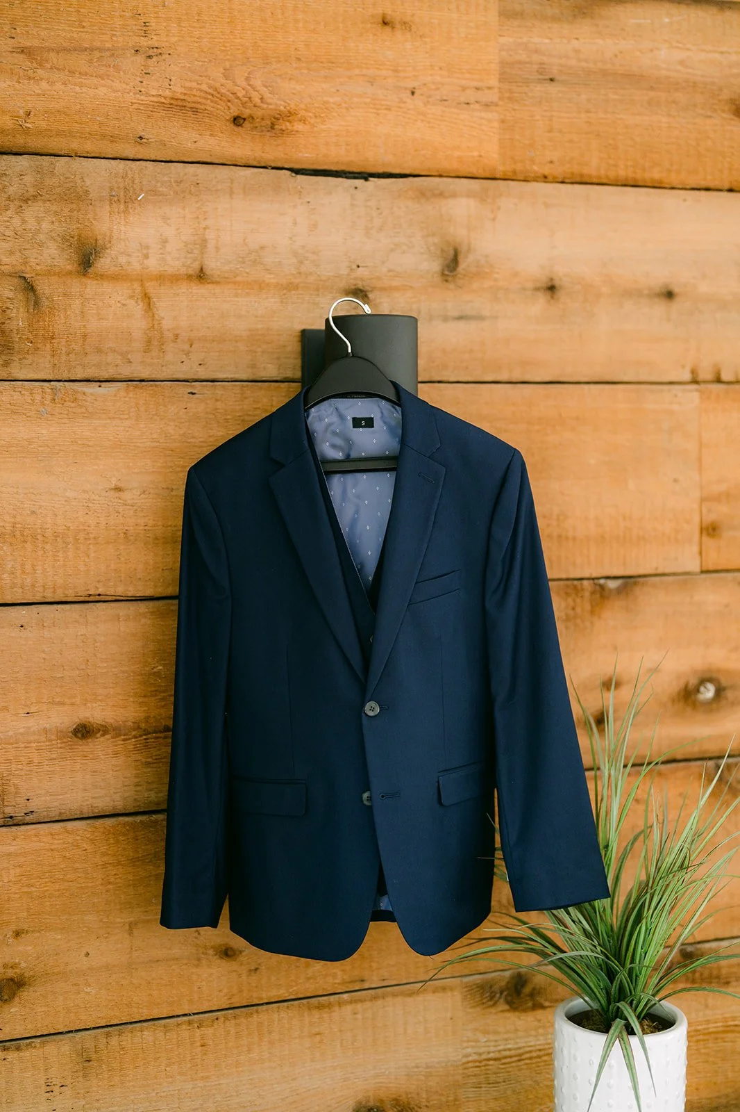 Groom's navy suit hanging on a wood plank wall