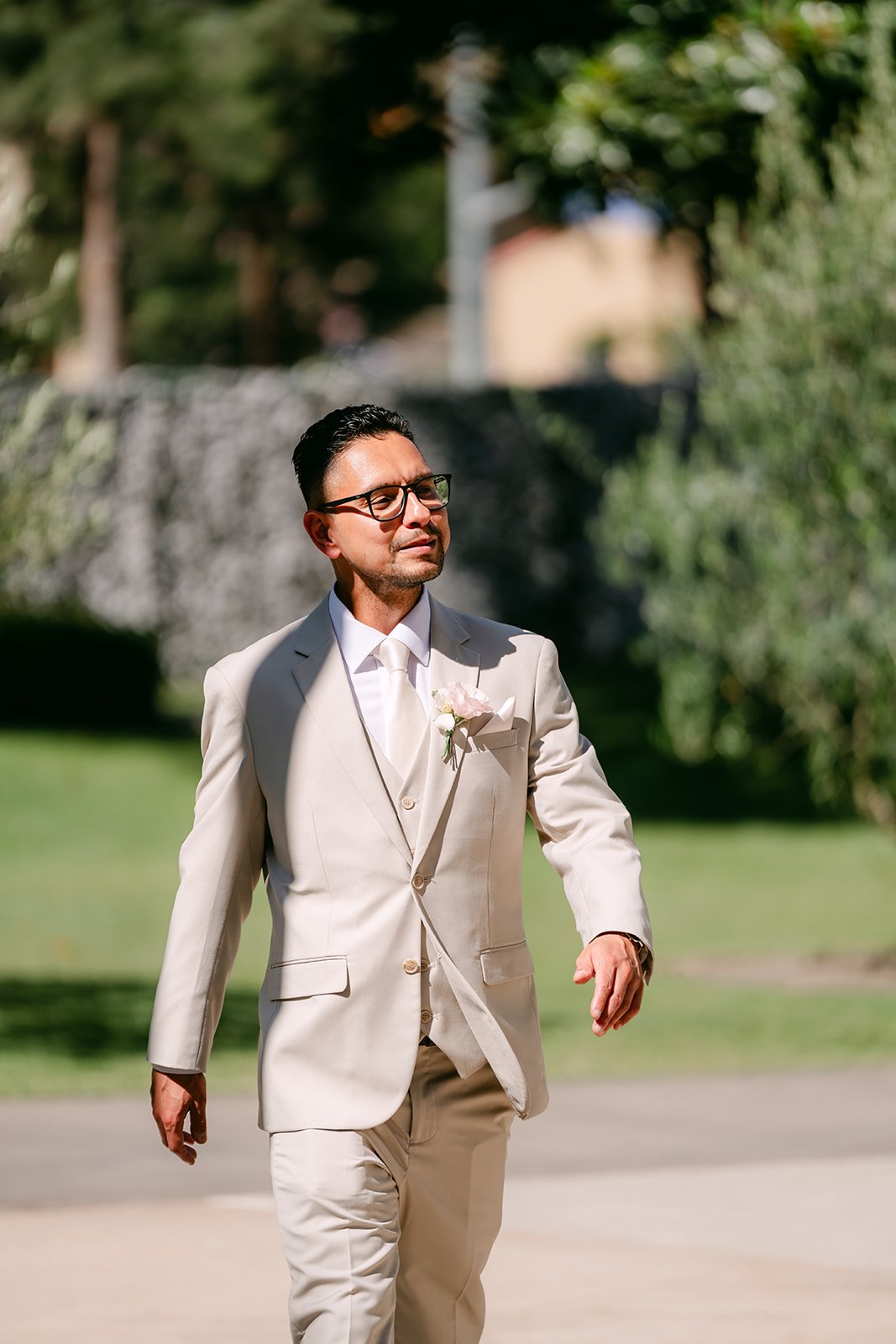 Kevin smiling as he walks down the aisle in his champagne suit.
