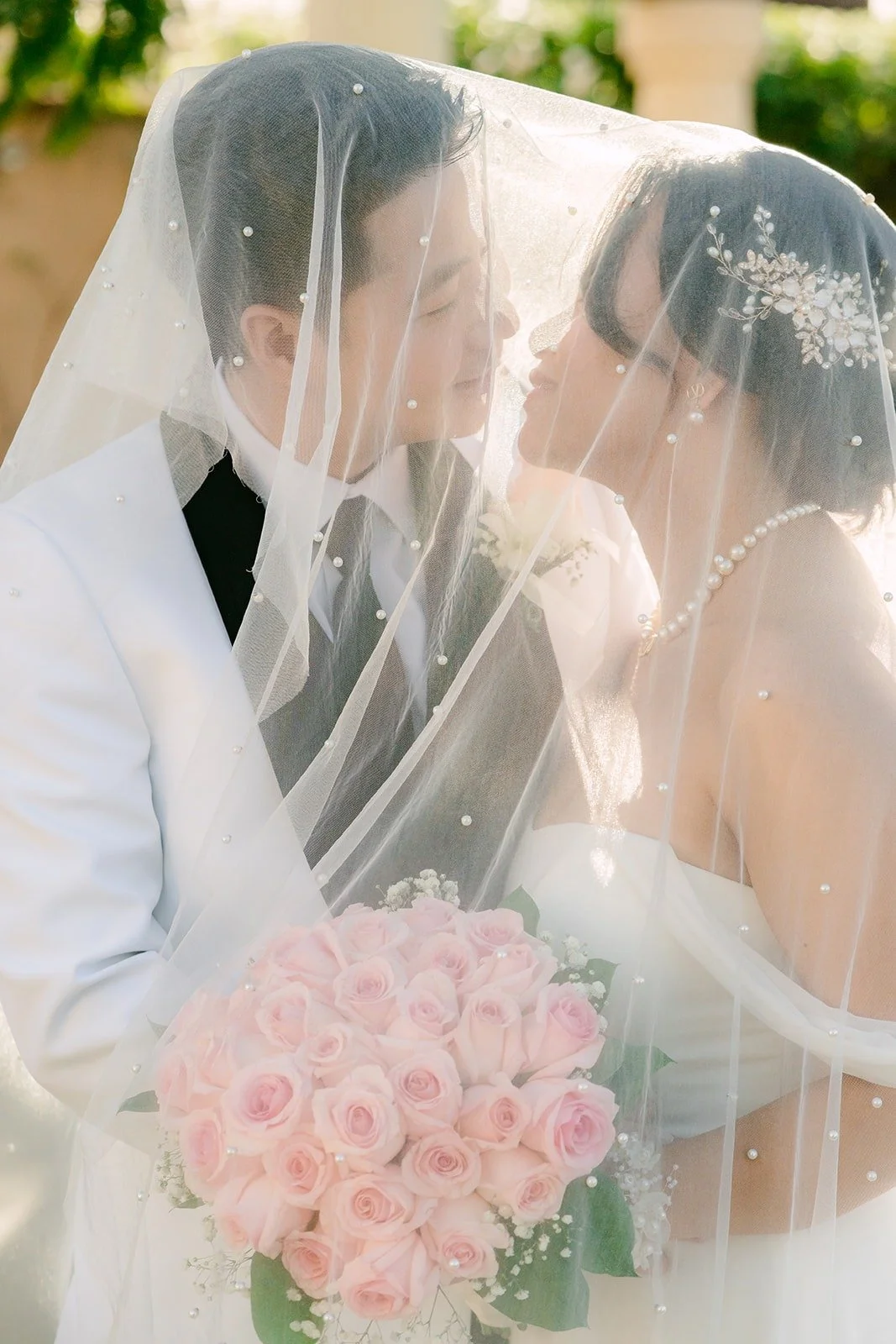 Ivy and Chungman under her veil with pink roses in front