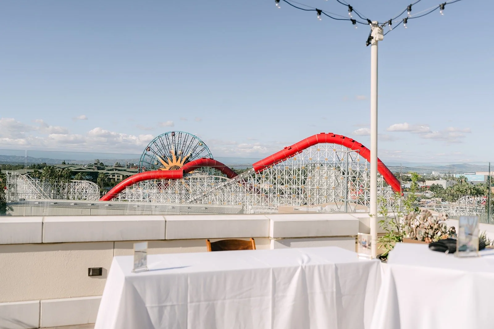 The Jewel Terrace set for cocktail hour with a view of the roller coaster beyond