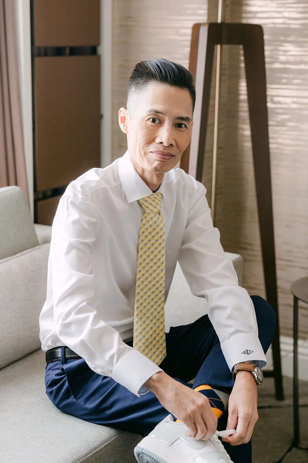 Bobby in his navy suit pants and gold tie getting ready.