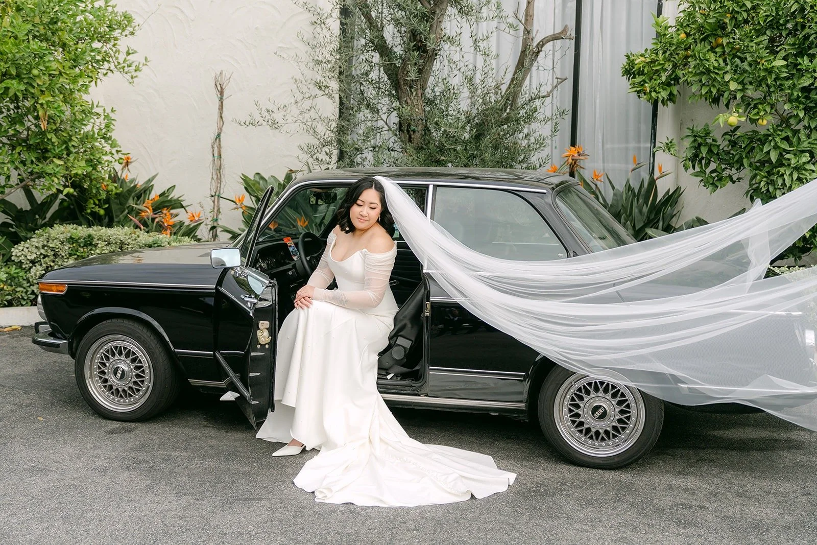 Vivian's veil trailing beside a vintage black car