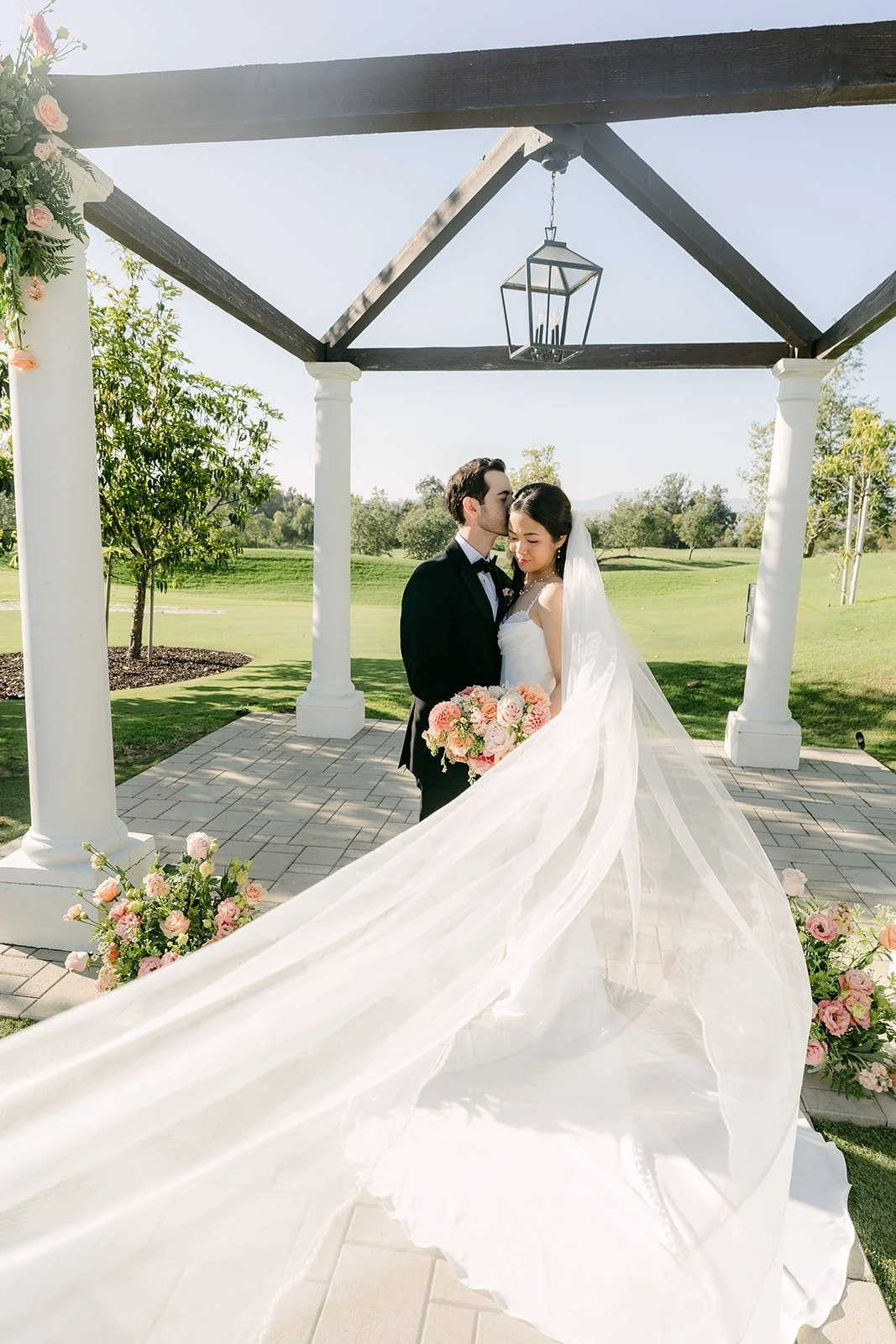 Stephanie's veil sweeping across the pagoda walkway as they kiss