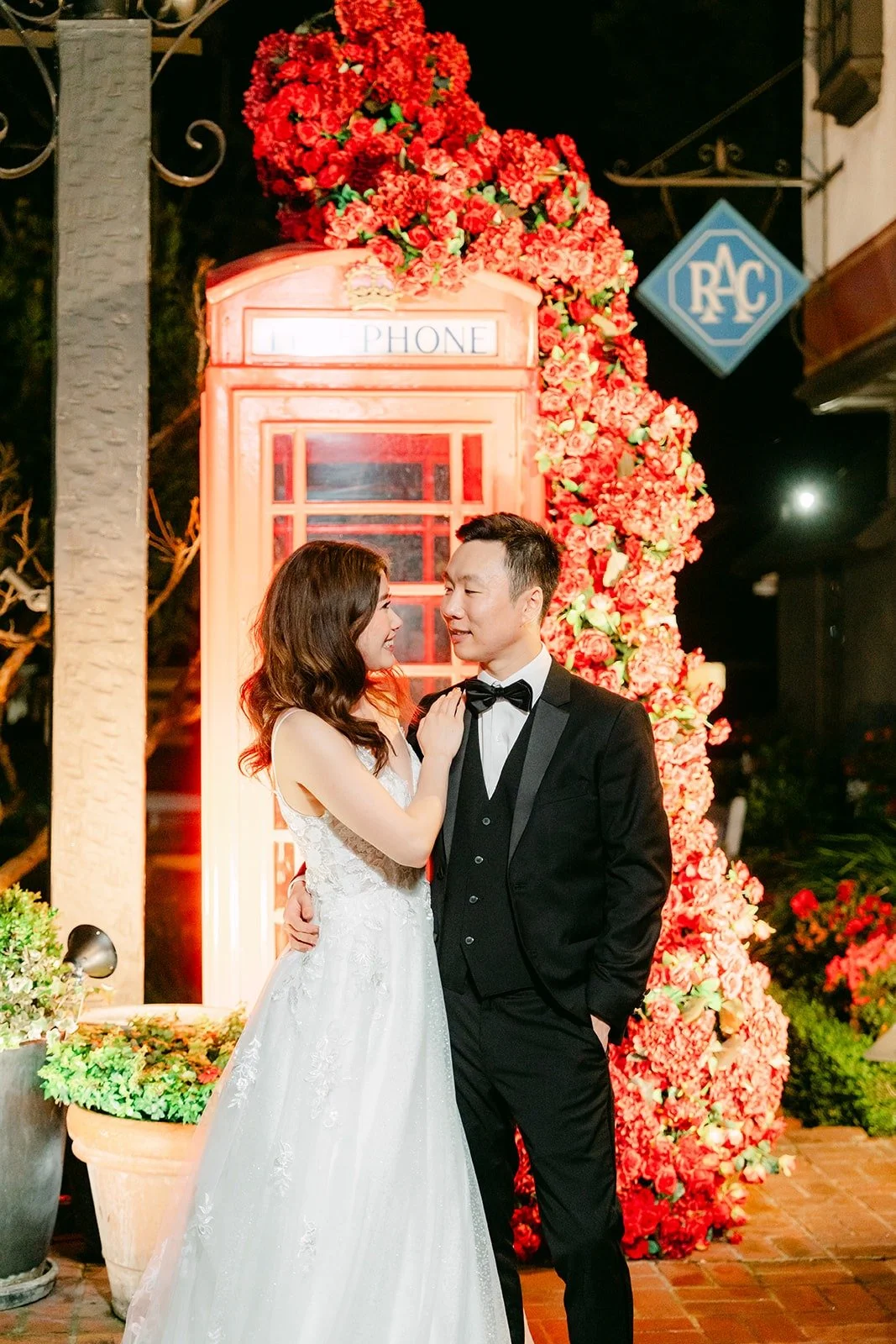 Valerie and Jason smiling at each other beside the roses at night