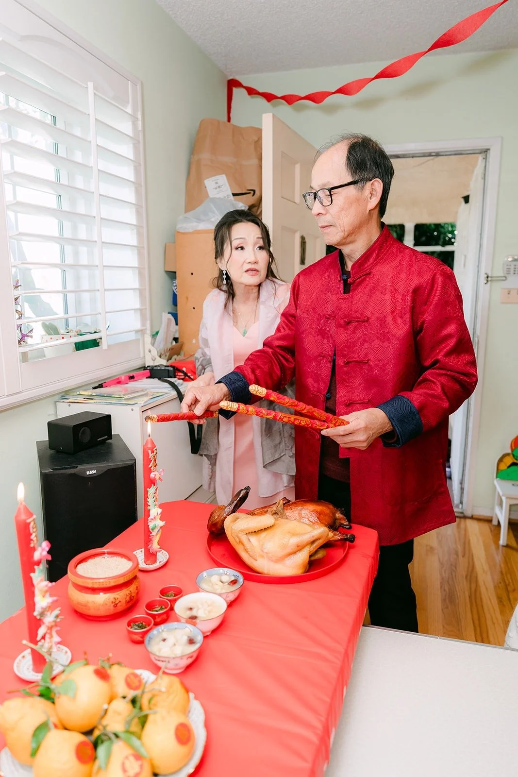 A family member in a red jacket arranges fruit and tea cups on the tea ceremony table