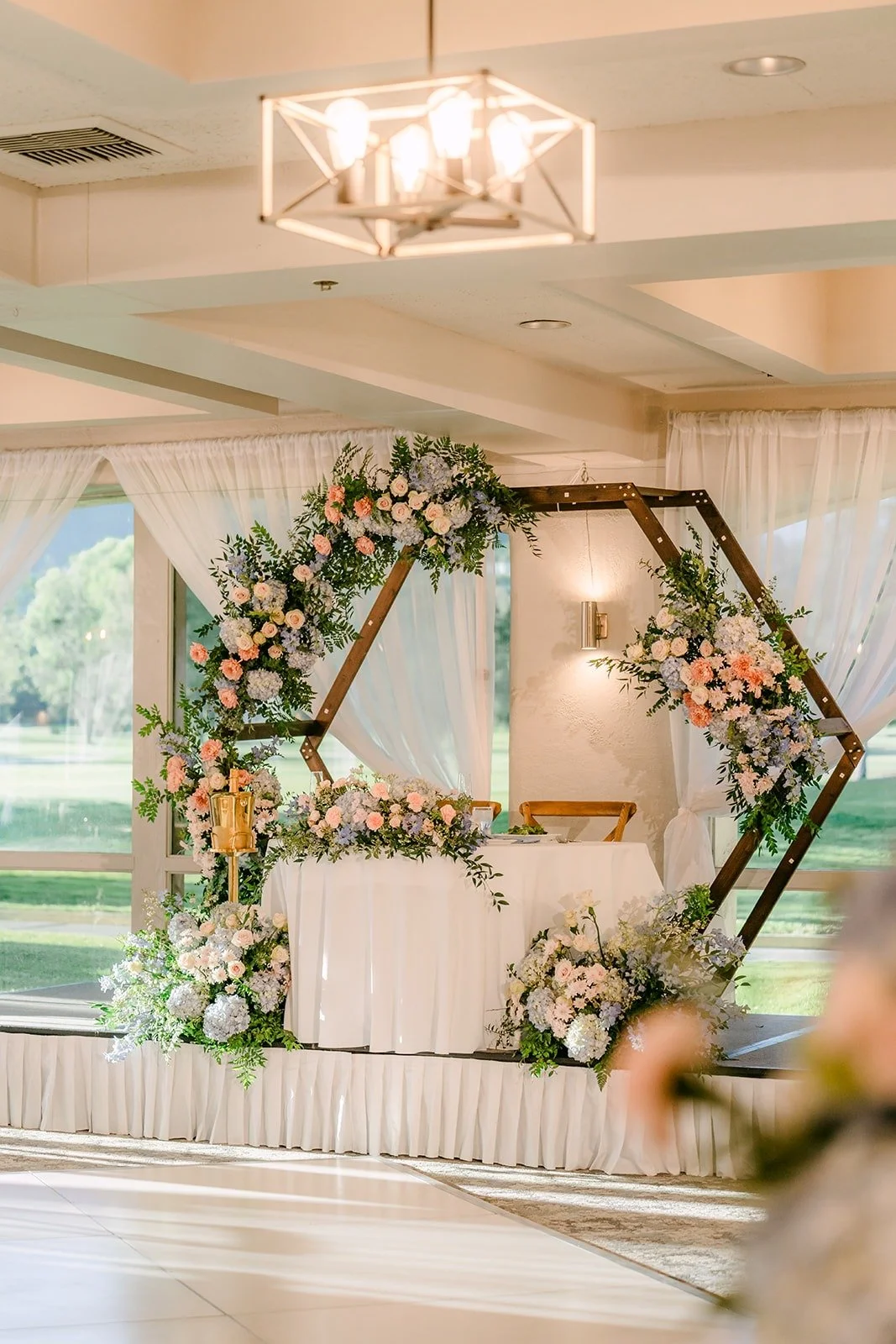 Sweetheart table under a hexagon arch of flowers in the ballroom