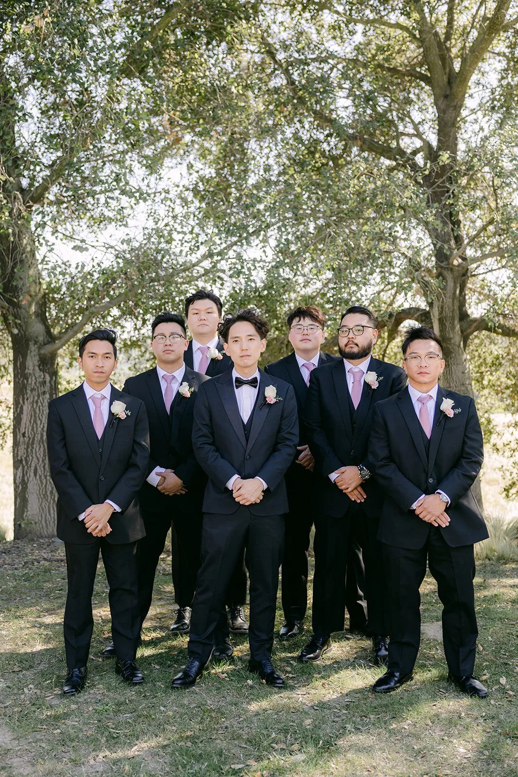 Tony with his groomsmen in black tuxedos under the trees at Vellano Estate