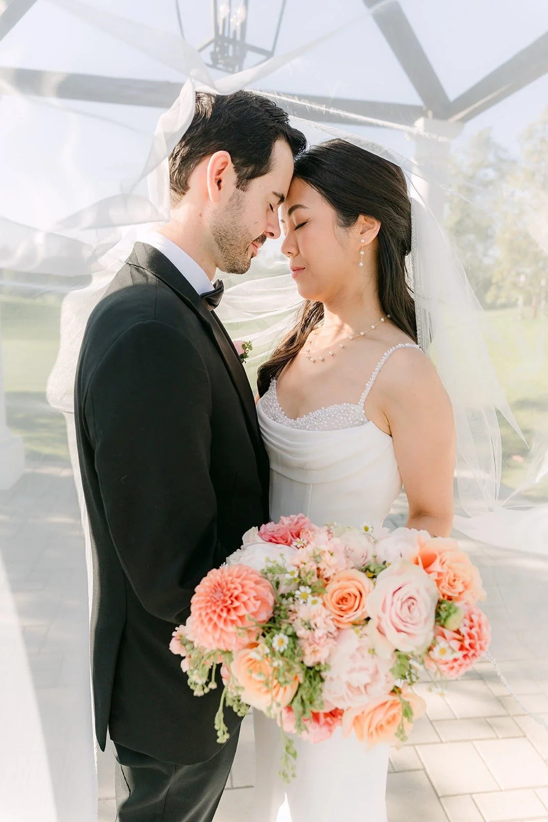 Stephanie and Kevin with their eyes closed, foreheads together under the pagoda at Sterling Hills