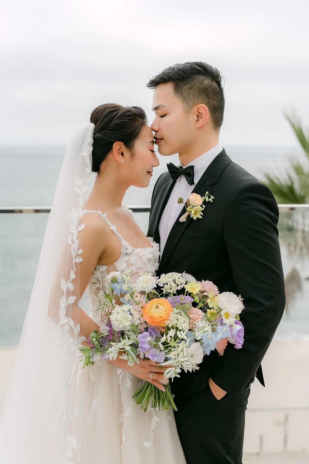 Kylie and Mario forehead to forehead against an overcast ocean sky