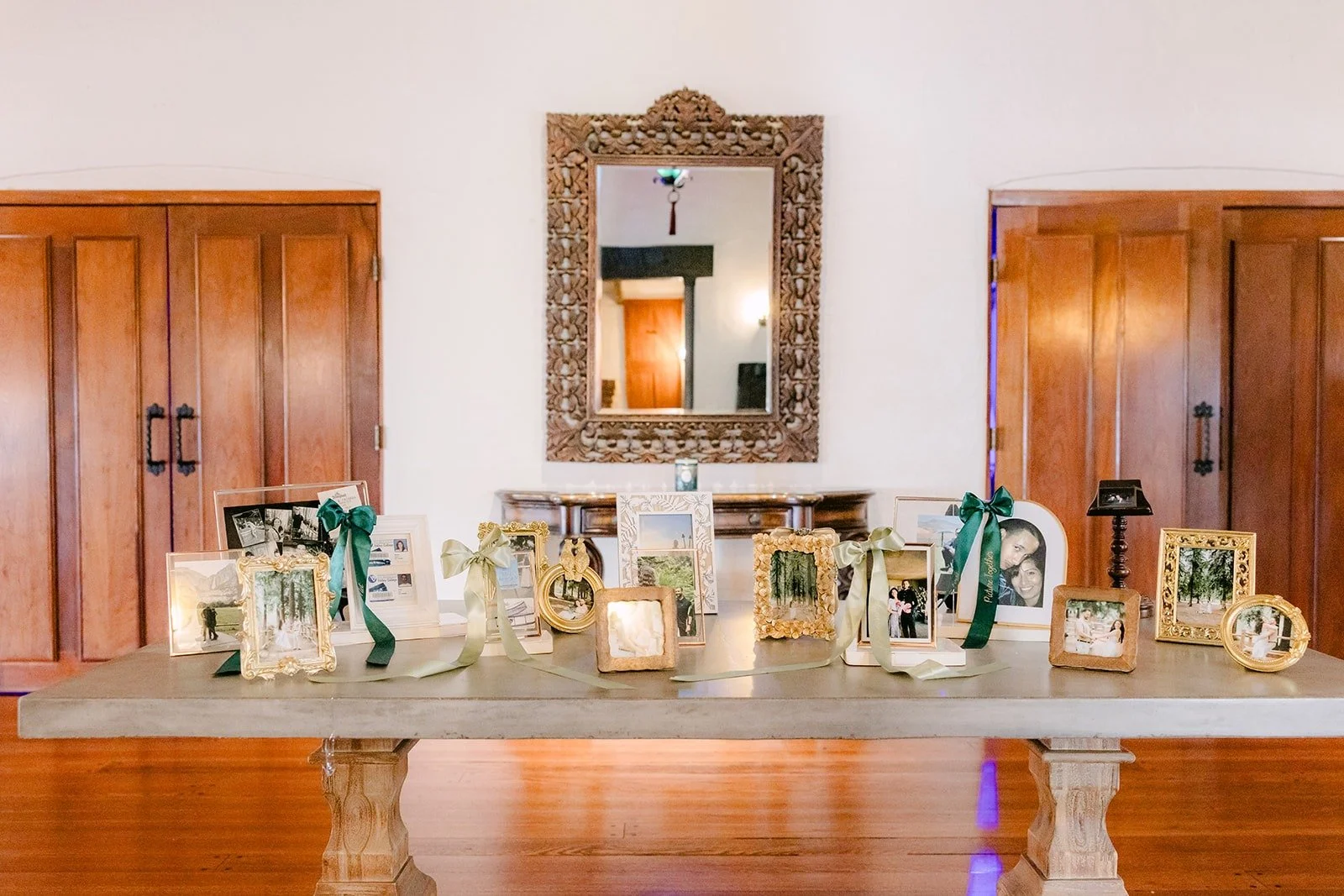 A memory table with framed photos and candles beneath a gold mirror