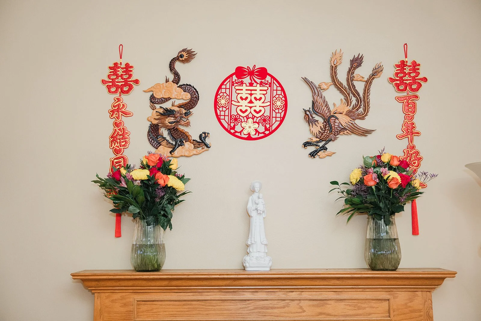 Gold dragon and phoenix decor with flowers on the mantel.
