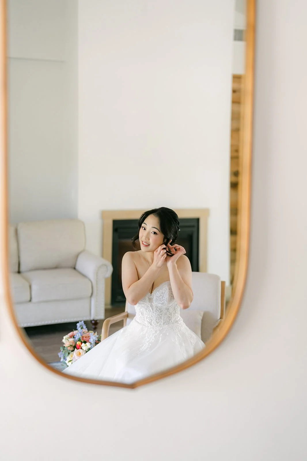 Yishan in her wedding gown reflected in an arched mirror in the Galway Downs bridal suite
