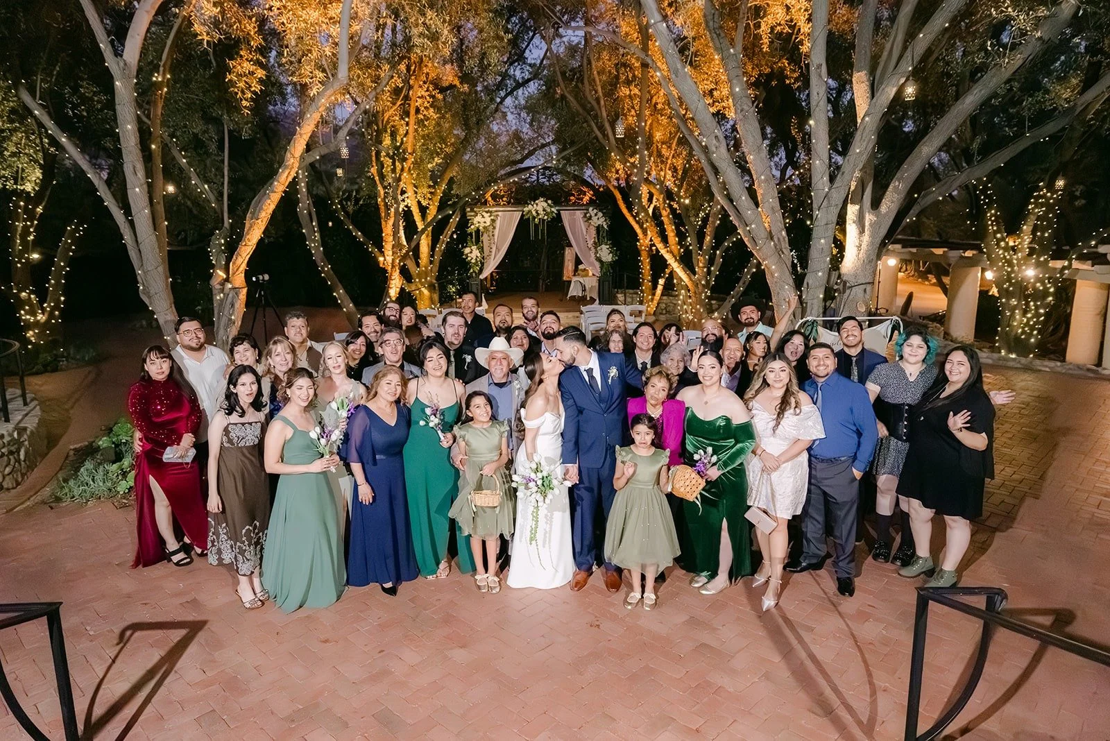 Mariana and Danny with all of their guests under the lit trees, photographed by One and Only Production