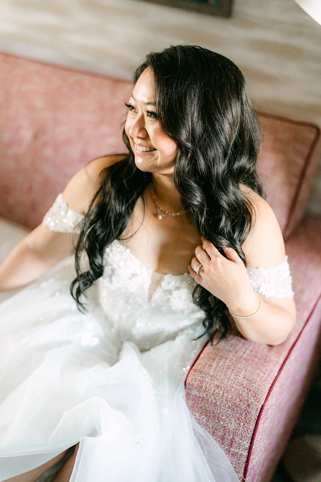 Jennifer smiles while sitting on the sofa in her gown