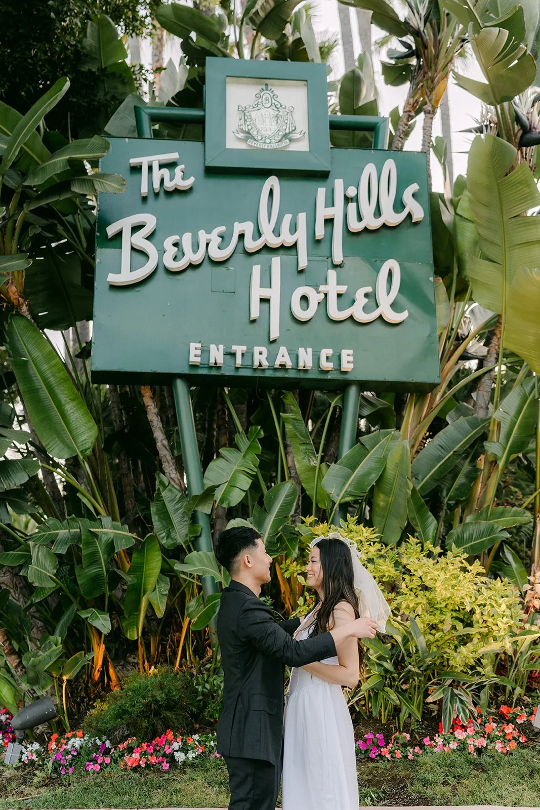 Jadee and Richard stand beneath the Beverly Hills Hotel entrance sign.
