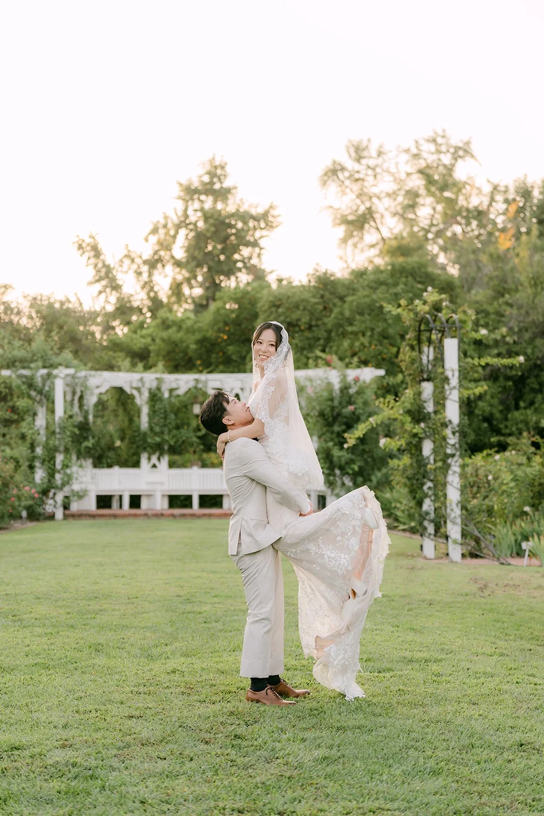 Wen dipping Elaine in front of the white lattice pergola.