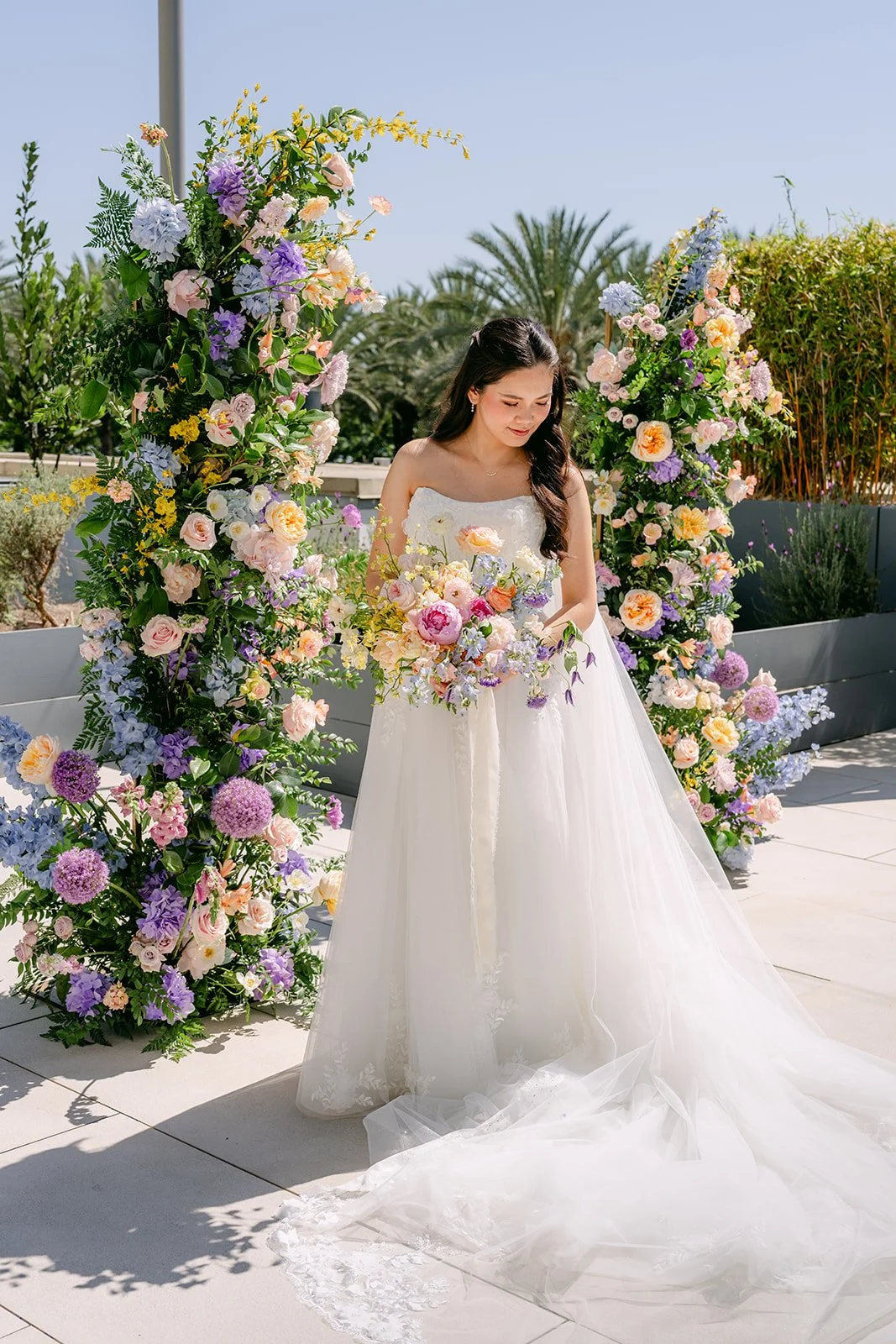 Full length bridal portrait with her train spread beside the ceremony florals