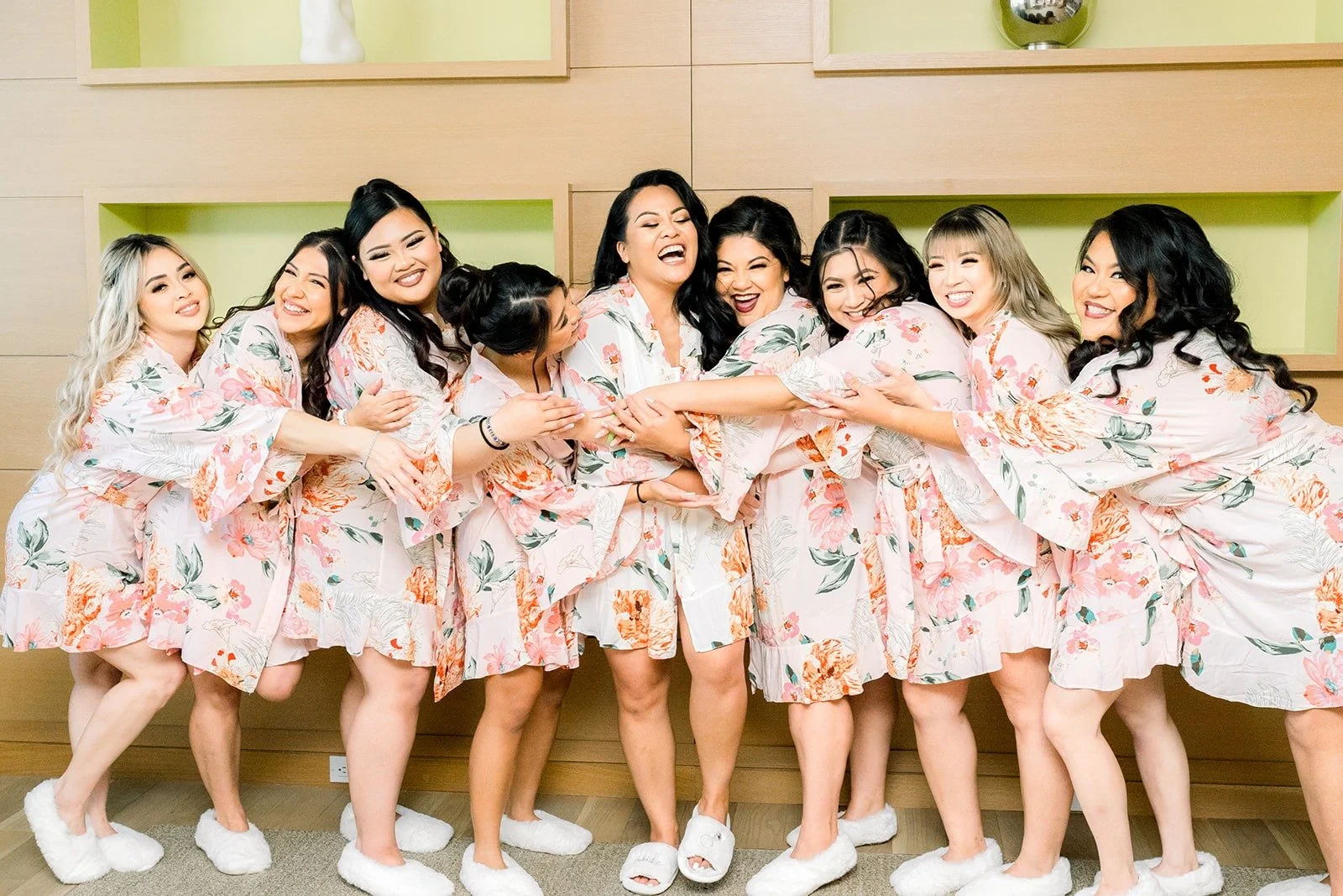 Betsy and her bridesmaids laughing in matching floral robes at Hyatt Regency Long Beach