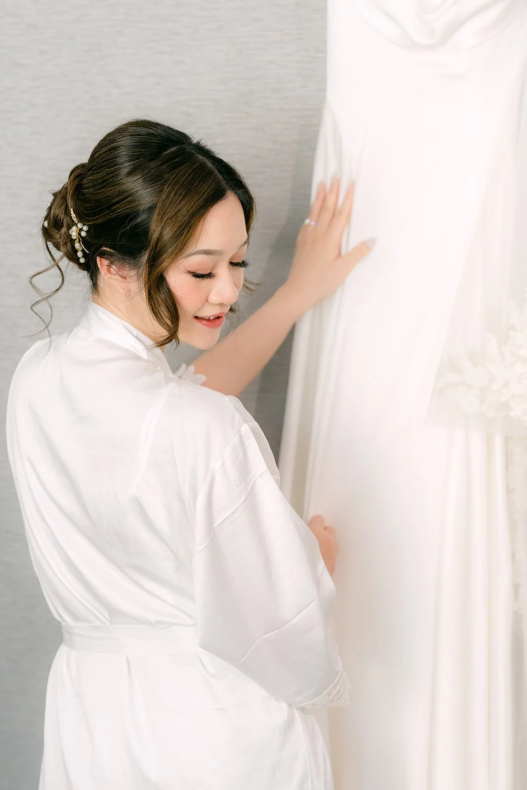 Amanda reaching for her gown by the window.