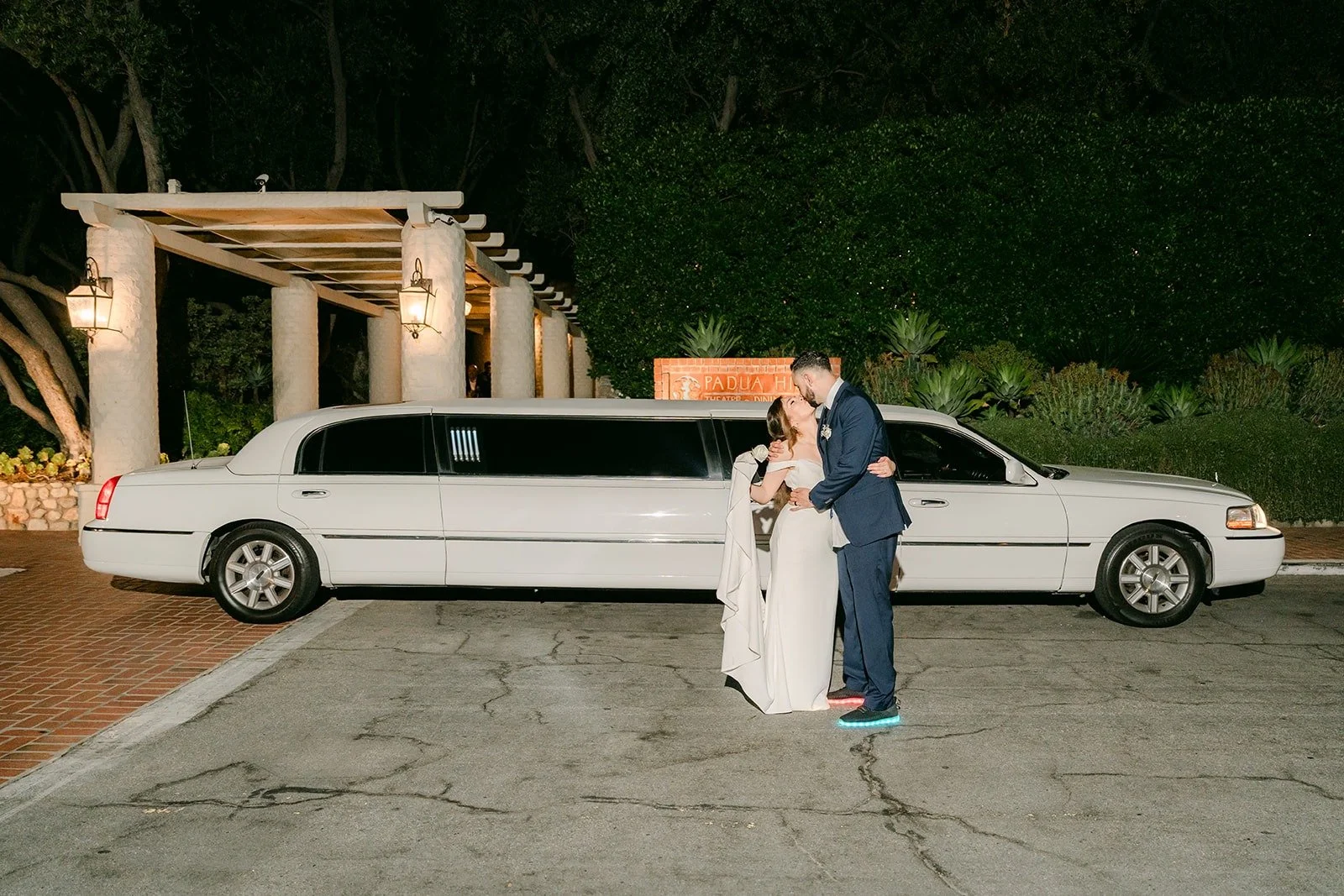 Mariana and Danny kissing beside a white stretch limousine