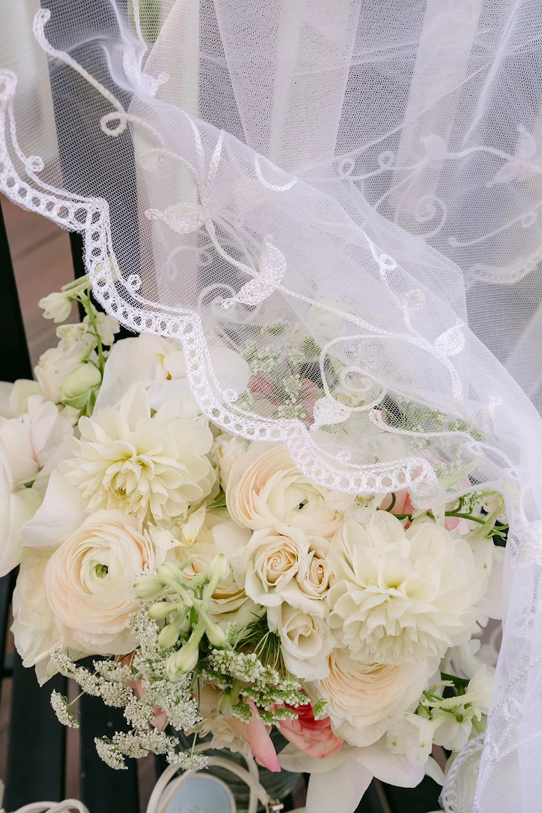 Nicole's ivory rose and garden bouquet resting on her lace veil.