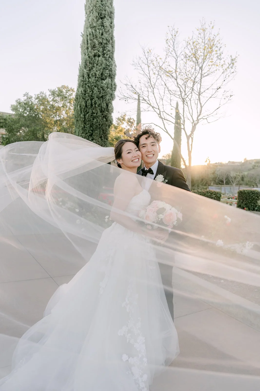 Veil sweeping across the frame as the couple laughs at golden hour
