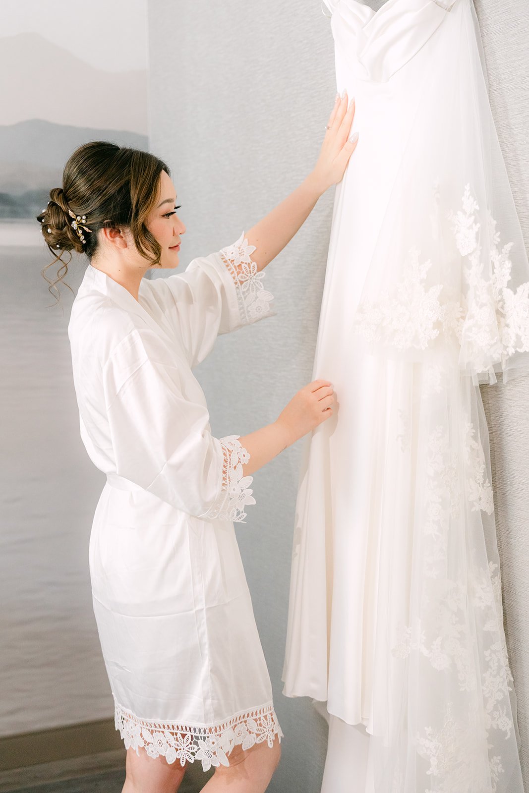 Amanda in a white robe looking at her gown before getting dressed.