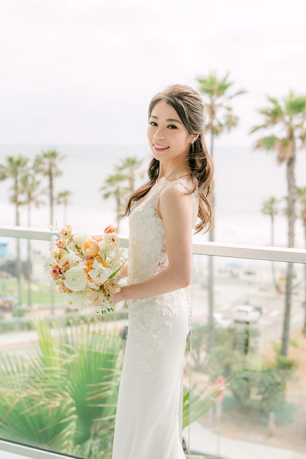 Angela holding her peach and ivory bouquet on the ocean view balcony
